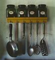 Kitchen utensils hanging below a spice rack