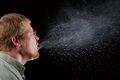 A person sneezing, illustrating airborne pathogen transmission.