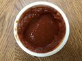 An open cup of marinara sauce from Domino's